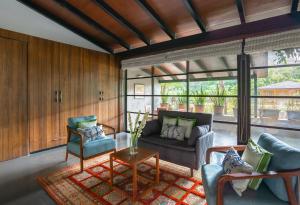 a living room with a couch and chairs and a table at LohonoStays Villa Orchard House in Revas
