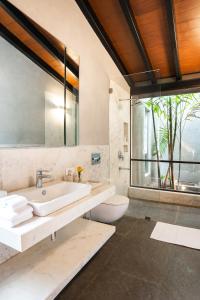 a bathroom with a sink and a toilet and a window at LohonoStays Villa Orchard House in Revas