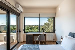 a bedroom with a desk and a large window at Dioni by PosarelliVillas in Kounoupidhianá +28 photos