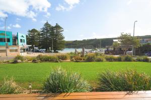 ein Park mit Gras und Wasser in der Unterkunft Loch Ard Motor Inn in Port Campbell