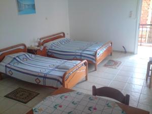 two beds sitting in a room with a tiled floor at TEO Studios in Kastrosikia