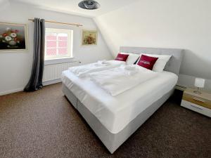 a bedroom with a large white bed with red pillows at Groegers Ferienzimmer in Hohwacht