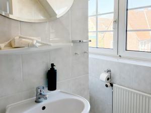 a white bathroom with a sink and a window at Groegers Ferienzimmer in Hohwacht +18 photos