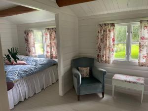 um quarto com uma cama, uma cadeira e janelas em Charming Cottage em Roskilde