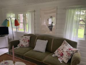 uma sala de estar com um sofá verde com almofadas em Charming Cottage em Roskilde