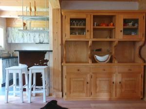 cocina con armario de madera y 2 taburetes en Chalet Dalpe by Quokka 360 - chalet among pastures and forests en Dalpe