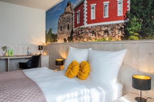 1 dormitorio con cama blanca y almohadas amarillas en Hotel Restaurant Elbebrücke en Oranienbaum-Wörlitz