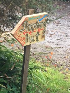 a sign on a wooden pole with graffiti on it at Relax in the unique and cosy Off-grid Eco Shepherd's hut Between Heaven and Earth in Mountshannon