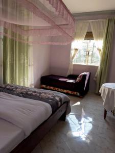 a bedroom with a bed and a chair and a window at Contra Hotel in Jinja