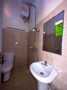 a bathroom with a sink and a toilet and a mirror at Contra Hotel in Jinja