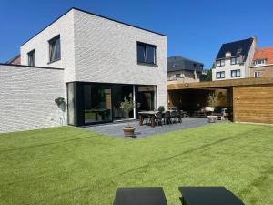 a house with a large yard with a patio at Feel@Home Aan Zee in Middelkerke