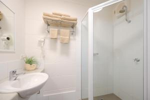 a white bathroom with a shower and a sink at Loch Ard Motor Inn in Port Campbell