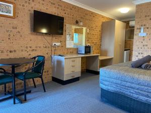 Cette chambre comprend un lit, une table et un bureau. dans l'établissement Aberdeen Motel, à Aberdeen