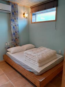 木浦市にあるDeluna Houseのベッド(白いシーツ付)、窓が備わります。