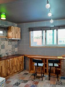 a kitchen with wooden cabinets and two stools at Deluna House in Mokpo