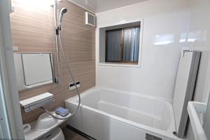 a bathroom with a tub and a toilet and a window at 旅time 住吉大社 Sumiyoshi shrine in Osaka