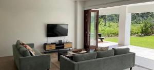 a living room with two couches and a flat screen tv at Temata Estate Rarotonga in Rarotonga
