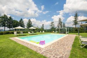 een zwembad in een tuin met stoelen en parasols bij Casale Montelucci by VacaVilla in Gaiole in Chianti