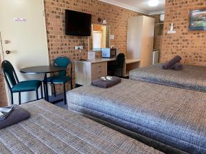 a hotel room with two beds and a table and chairs at Aberdeen Motel in Aberdeen