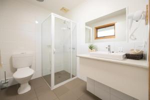 a white bathroom with a toilet and a sink at Loch Ard Motor Inn in Port Campbell
