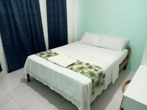 Schlafzimmer mit einem Bett mit weißer Bettwäsche und Kissen in der Unterkunft Larot's Vacation House - Rooms Only in Siquijor