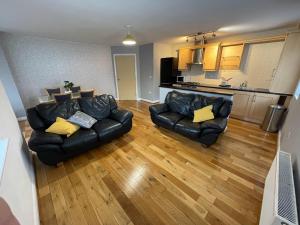 uma sala de estar com dois sofás de couro e uma cozinha em Stylish, Bright & Spacious 2 Bed Apartment with Parking, Fulwood, Preston em Grimsargh