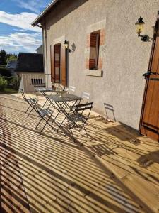 a patio with a table and chairs on a deck at Maison Les Roses in Marmagne +7 photos