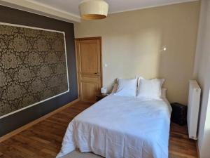 a bedroom with a white bed and a wall at Maison Les Roses in Marmagne