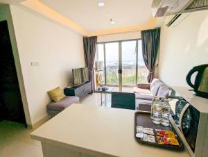 a kitchen and living room with a couch and a table at Lovina 9-17 at Harbour Bay Residence(Near Ferry) in Batu Ampar
