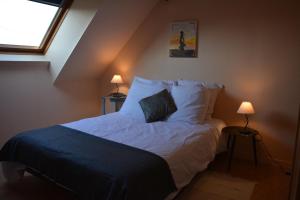 a bedroom with a bed with white sheets and a window at La Villa Bernard in Varennes-sur-Loire