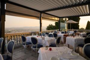een restaurant met witte tafels en stoelen op een balkon bij Castello Bonaria Wine & Spa Resort in Campiglia Marittima