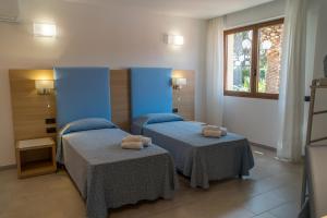 una camera da letto con due letti con asciugamani sopra di Hotel Oasis ad Alghero