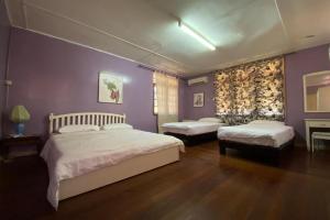 um quarto com 2 camas e uma parede roxa em OYO Home 90851 Rb Homestay & Farms 2 em Kuching