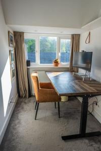 um quarto com uma secretária, uma cadeira e janelas em Beautiful house close to Amsterdam Beach and Haarlem em Aerdenhout