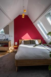 um quarto com uma cama com uma parede vermelha em Beautiful house close to Amsterdam Beach and Haarlem em Aerdenhout