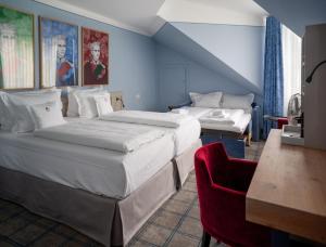 ガルヒング・バイ・ミュンヘンにあるホテル ケーニッヒ ルートヴィッヒ IIのベッド2台と赤い椅子が備わるホテルルームです。
