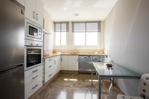 a kitchen with white cabinets and a glass table at Veoapartment Arenal in Seville