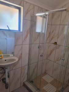 a shower with a glass door next to a sink at Home Life Guesthouse in Midrand