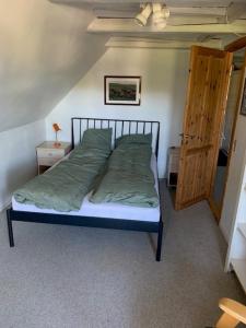 a bedroom with a bed with green sheets and a wooden door at Dyrlundgaard tilbyder charmerende ferielejlighed. in Helsinge