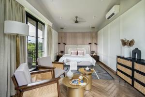 a bedroom with a bed and a table and chairs at LohonoStays Riyuvann Estate in Alibag +28 photos