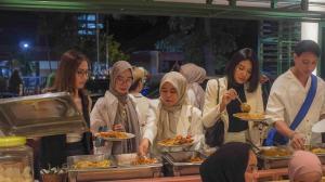 un grupo de personas de pie alrededor comiendo comida en The Win Hotel Surabaya, en Surabaya