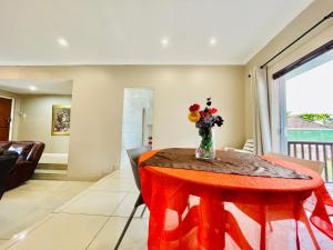 a dining room table with a vase of flowers on it at Entire House in Beacon Bay - Family or Group Retreat - Swimming Pool - Multiple Braais in East London