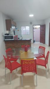 a dining room with a glass table and red chairs at Casa de praia com picina 2 in São José da Coroa Grande