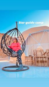 a woman sitting in a swing chair on a stage at Star Guide Camp in Wadi Rum