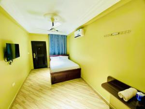 Cette petite chambre jaune comprend un lit et une télévision. dans l'établissement Abanaba lodge& Restaurant, à Kumasi