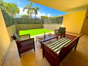 een terras met een tafel en stoelen en een gazon bij Tropicalidays Jardines del Teide in Puerto de la Cruz