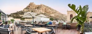 a restaurant with tables and chairs with a mountain in the background at Hotel La Milagrosa in Alicante