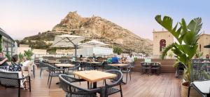 a restaurant with tables and chairs with a mountain in the background at Hotel La Milagrosa in Alicante