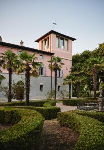 un bâtiment avec des palmiers en face d'un jardin dans l'établissement Villa Liverzano, à Brisighella