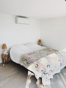een witte slaapkamer met een bed met een kleurrijke deken bij Cabanon moderne, les pieds dans l'eau in Le Pradet